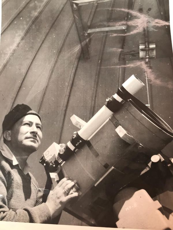 Un hombre con gorro mira por el ocular de un telescopio dentro de una cúpula.